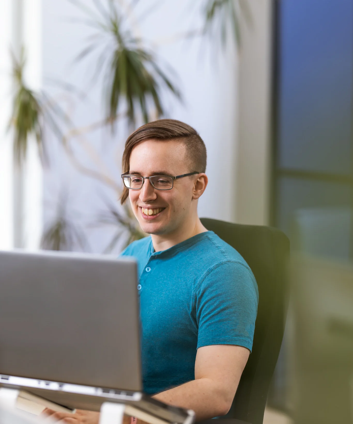 homme souriant assis face à son ordinateur.
