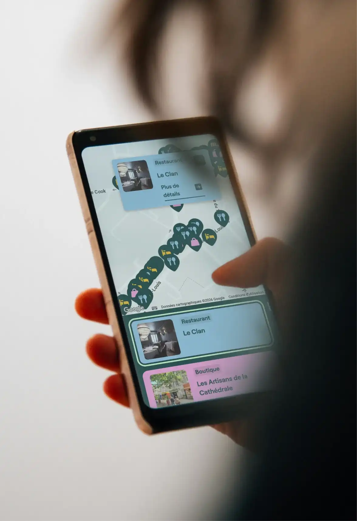 Une femme tient dans sa main un cellulaire affichant la carte interactive de la Société de développement commercial du Vieux-Québec.